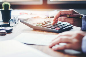 Hand holding pen, punching numbers into a calculator