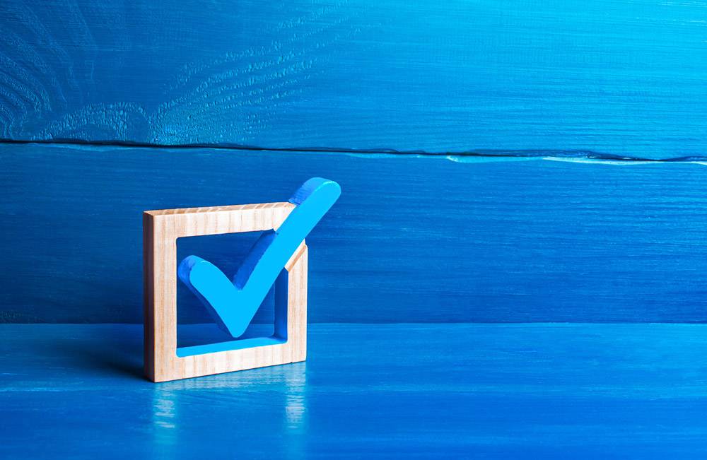 wooden checkbox against blue background. verifications concept.
