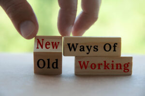 Hand touching wooden blocks saying "new ways of working"