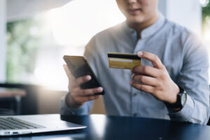 Person holding credit card while checking phone